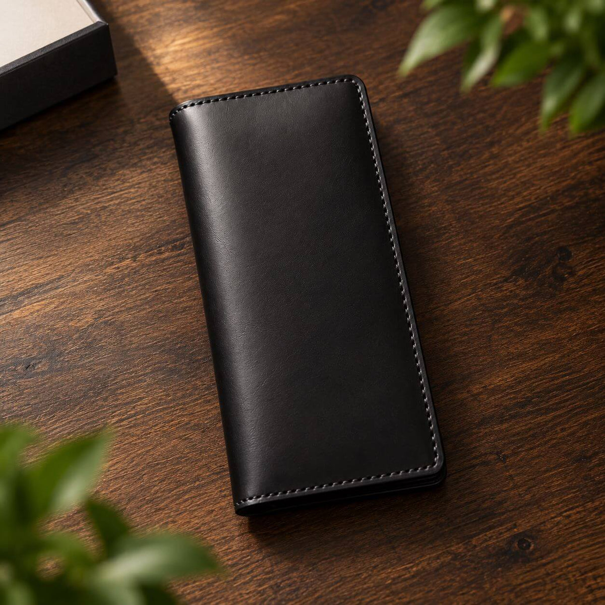 Black handmade full grain leather long wallet on a modern desk